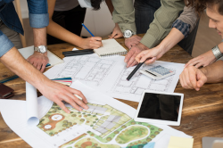 House design on counter with two people working on drawing.