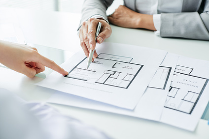 House design on counter with two people working on drawing.