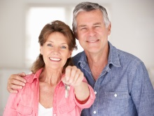 Happy middle aged couple with keys in hand.